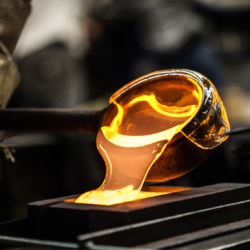 Gießprozess in der Glasindustrie: Heiße, flüssige Glasschmelze wird in eine Form gegossen – industrielle Fertigung mit Fokus auf saubere Kühl- und Filtrationsprozesse.